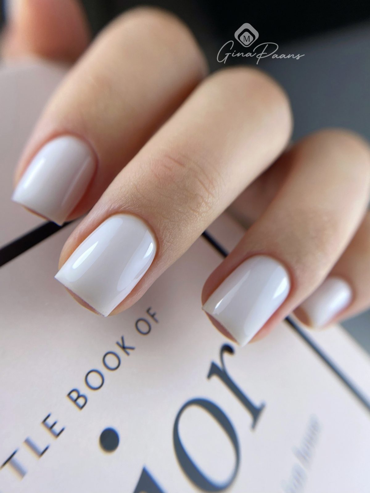 Korte melkwitte nagels op een boek